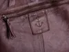 A close-up view of a brown leather bag with a zipper and a brand tag. Produktbild-Vorschau
