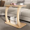 A wooden C-shaped side table with a stack of books on its lower shelf, placed next to a sofa. The table top holds a plate of donuts and a cup of coffee. Náhled obrázku produktu