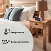 A bedside table with a digital clock and a lamp, next to a bed with pillows. Anteprima dell’immagine prodotto