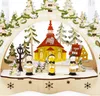 A wooden Christmas decoration featuring a church, houses, trees, and figures in a snowy scene. Produktbild-Vorschau