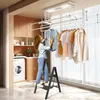 A woman is using a stepladder to hang clothes on a ceiling-mounted drying rack in a laundry room. Voir les images du produit