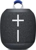 A dark gray portable speaker with a blue handle on top. Produktbild-Vorschau