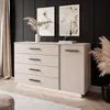 A modern dresser with black handles and LED lighting, styled in a room with artwork and dried plants. Produktbild-Vorschau