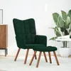 A dark green velvet armchair and ottoman set on a light-colored rug, with a floor lamp and a large potted plant in the background. Náhľad obrázku produktu
