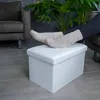A person's feet in knitted socks rest on a white ottoman in a living room setting. Náhled obrázku produktu