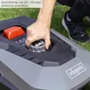 A person's hand is adjusting a dial on a robotic lawnmower. Produktbild-Vorschau