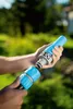 Two hands connecting two blue hose connectors outdoors. Voir les images du produit