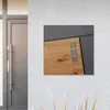 A modern mailbox with a wood-look panel is mounted on a textured gray wall next to a gray door. Produktbild-Vorschau
