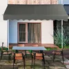 An outdoor patio scene with a table and chairs set up under a gray awning. Anteprima dell’immagine prodotto