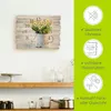 A wall clock with a floral design is shown on a wall, with shelves and kitchen items below. To the right, there are marketing graphics highlighting product features. Produktbild-Vorschau