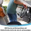 Schwarzes Autositzkissen auf einem Autositz, eine Person steigt ins Auto, und ein Hund schaut zu Náhľad obrázku produktu