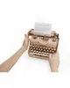 Hands are holding a wooden typewriter model with paper in it. Podgląd zdjęcia produktu