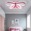 A bedroom with a butterfly-shaped ceiling light, a bed with pink bedding, and framed pictures on the wall. Produktbild-Vorschau
