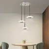 A modern dining area with a round table and chairs, illuminated by a set of three pendant lights. Anteprima dell’immagine prodotto