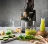 A Kuvings EVO820 Signature slow juicer is set up with fresh ingredients and juice, suggesting a healthy lifestyle. Podgląd zdjęcia produktu