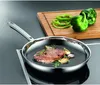 A steak is being cooked in a frying pan on a stovetop, with green bell peppers and a cutting board in the background. Podgląd zdjęcia produktu