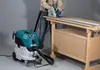 A person is using a circular saw with a track guide, connected to a wet/dry vacuum cleaner, on a workbench. Podgląd zdjęcia produktu