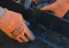 Hands wearing orange gloves are installing black garden edging into the soil. Náhľad obrázku produktu