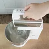 A hand is pressing buttons on a white hand mixer over a metal bowl. Anteprima dell’immagine prodotto
