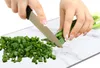 Hands chopping green onions on a marble cutting board. Produktbild-Vorschau