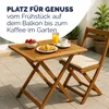 A wooden folding table and chair set on a patio, set for breakfast with strawberries, a croissant, and coffee. Produktbild-Vorschau