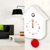A modern living room with a black sofa, a white coffee table, and a white cuckoo clock on the wall. Anteprima dell’immagine prodotto