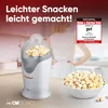 A woman is standing in a kitchen with a popcorn maker and a bowl of popcorn. Náhled obrázku produktu