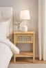 A bedside table next to a bed, with a lamp and a small vase of greenery on top. Podgląd zdjęcia produktu