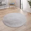 A round, gray rug is placed on a wooden floor in a room with a chair and a shelf.