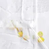 A close-up view of a white sheer curtain with a leaf pattern, featuring lemons and a clear plastic tube. Produktbild-Vorschau