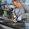 A man is using an angle grinder to cut metal in a workshop. Produktbild-Vorschau