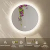 A round LED mirror with a floral design and illuminated border, displayed above a bathroom counter with toiletries. Anteprima dell’immagine prodotto