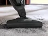 A vacuum cleaner head is shown cleaning a carpet, picking up dirt. Voir les images du produit