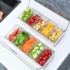 Two clear plastic containers filled with various fruits and vegetables, arranged on a white countertop. Produktbild-Vorschau