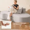 A woman is sitting on a light gray sofa, reading a magazine. There is a close-up inset image showing a hand pressing into foam. Náhľad obrázku produktu