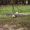 A fake bird of prey is hanging from a tree branch outdoors. Náhled obrázku produktu