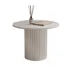 A round coffee table with a fluted base, a bottle of diffuser, and a book on top, isolated on a white background. Voir les images du produit