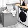 A laundry basket with two compartments is shown next to a washing machine in a laundry room. Produktbild-Vorschau