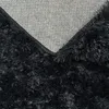 A close-up view of the underside and pile of a black shag rug. Produktbild-Vorschau