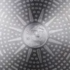 The bottom of a frying pan with a textured surface and a central logo. Náhled obrázku produktu