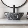 A marble-patterned vessel sink on a countertop with a faucet and a bottle of soap. Produktbild-Vorschau