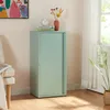 A mint green metal cabinet with a sliding door stands in a room next to a chair and a window with sheer curtains. Decorative items are placed on top of the cabinet. Náhled obrázku produktu