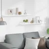 Two white shelves mounted on a white wall above a grey sofa. Voir les images du produit