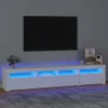 A modern white TV stand with blue LED lighting is shown in a living room setting, with a large black TV mounted on the wall above it. Produktbild-Vorschau