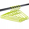 Several green plastic clothes hangers hanging from a black rod. Anteprima dell’immagine prodotto