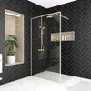A modern bathroom with a walk-in shower featuring a gold frame and black herringbone tiles. Produktbild-Vorschau