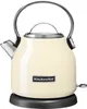 A cream-colored KitchenAid electric kettle with a silver handle and spout, sitting on a black base. Produktbild-Vorschau