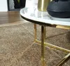 A close-up view of a round coffee table with a marble-look top and gold metal legs, placed on a patterned rug. Anteprima dell’immagine prodotto