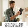 A man is holding a tablet and a mug, looking at the tablet screen. Produktbild-Vorschau
