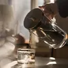 A hand is pouring water from a glass pitcher into a glass. Náhľad obrázku produktu